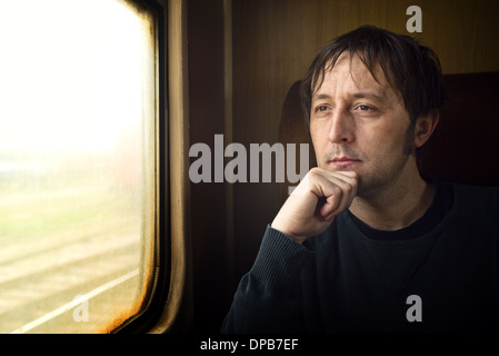 Traveling by train. Man traveling by train, looking through the dirty window. Stock Photo