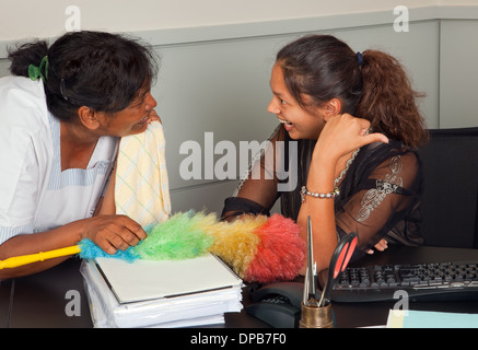 Cleaning woman and secretary talking gossip in the office Stock Photo