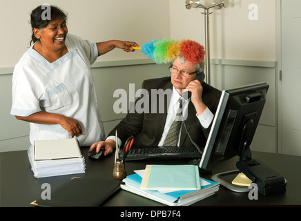 Funny cleaning woman cleaning the office of the manager including his face Stock Photo