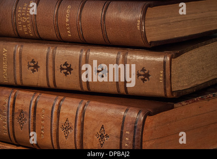 Horizontal stack of three old books in brown leather binding with dates showing on spine. Stock Photo