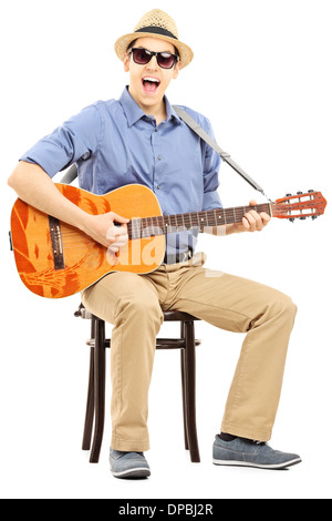 Man sitting on a chair and singing and playing an acoustic guitar ...