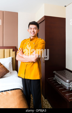 Asian Chinese baggage porter or bell boy or page bringing the suitcase of guests to the luxury hotel room Stock Photo