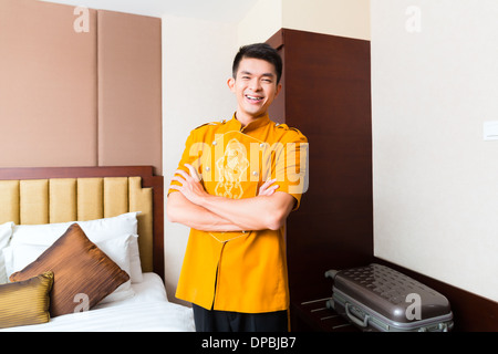 Asian Chinese baggage porter or bell boy or page bringing the suitcase of guests to the luxury hotel room Stock Photo