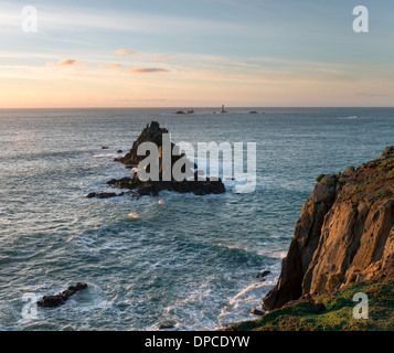 Rocky cliffs at Lands End in Cornwall with the Longships lighthouse in the distance Stock Photo