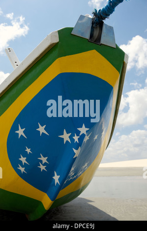 Fishing boat painted with bright Brazilian flag colors on the beach in Jericoacoara Brazil Stock Photo