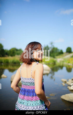 Young asian girl in a colorful maxi dress playing by a river in the summer Stock Photo