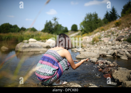 Young asian girl in a colorful maxi dress playing by a river in the summer Stock Photo