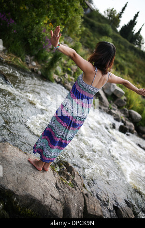 Young asian girl in a colorful maxi dress playing by a river in the summer Stock Photo