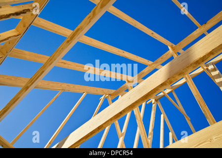 New construction home framing against blue sky, closeup of ceiling frame. Stock Photo