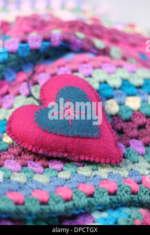 Pink and blue felt shabby chic heart on a crochet colorful afghan blanket , pinks, blues, greens, and creams , Stock Photo
