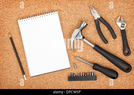 Set of tools on cork panel background with notepad for copy space Stock Photo