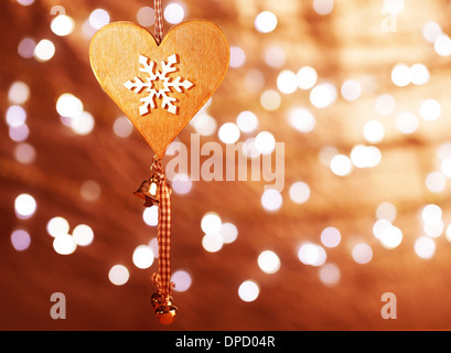 Beautiful wooden heart shaped New Year decoration with snowflake ornament hanging on blur shiny golden background Stock Photo