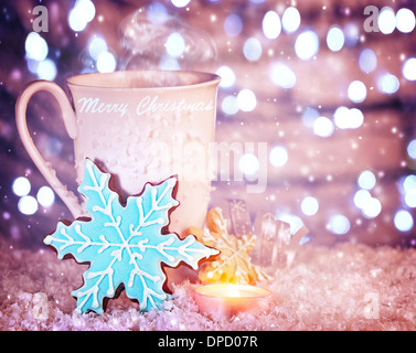 White cup of coffee with blue snowflake shaped gingerbread, warm cozy candle light, beautiful still life of Christmas dessert Stock Photo
