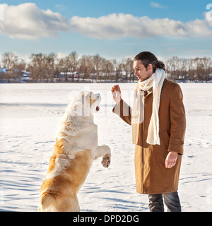 Man and central Asian shepherd playing with his dog outdoors Stock Photo