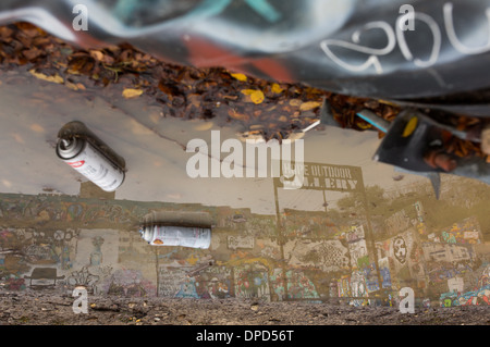 Empty spray cans lay in front of a graffiti wall in the HOPE Outdoor Gallery in Austin, Texas Stock Photo