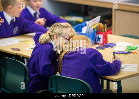 Two friends whispering in a primary school class Stock Photo