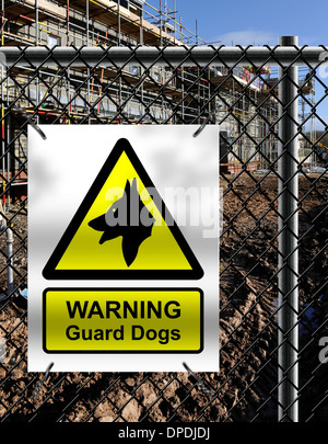 Building site security notice with ‘WARNING Guard Dogs’ sign fixed to perimiter fence. Stock Photo