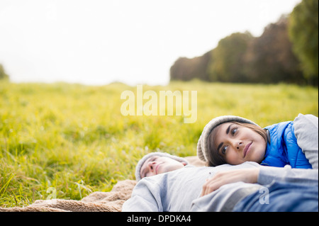 Young woman resting head on man's chest in park Stock Photo