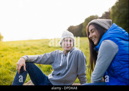Young couple sitting on grass laughing Stock Photo