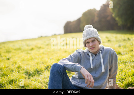 Portrait of young man sitting on grass wearing knit hat Stock Photo