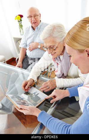 Happy senior woman looking at photos in photo album of her family Stock Photo