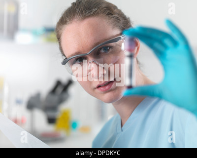 Technician holding bar coded blood sample in clinical laboratory Stock Photo