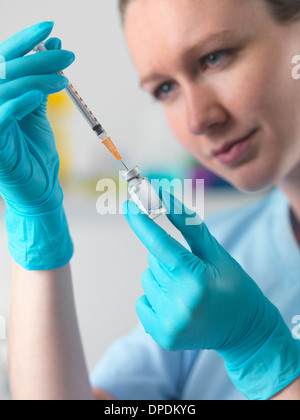 Healthworker holding up a syringe and vial, and filling the syringe in preparation for carrying out an injection Stock Photo