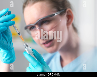 Healthworker holding up a syringe and vial, filling syringe in preparation injection Stock Photo
