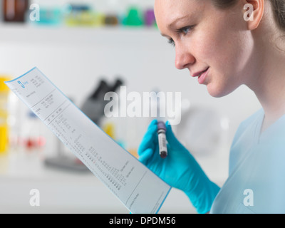 Technician holding blood sample in clinical laboratory with test results Stock Photo