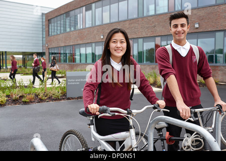 Teenager friends with cycles outside school Stock Photo