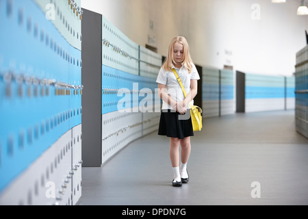 Unhappy schoolgirl walking alone in school corridor Stock Photo