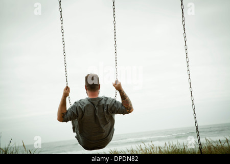 Mid adult man on beach swing Stock Photo
