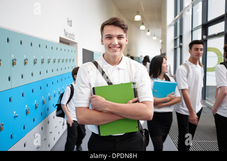 Portrait of teenage boy holding file in school corridor Stock Photo