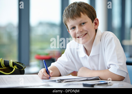 Portrait of schoolboy writing in class Stock Photo