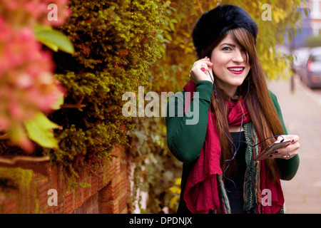 Young woman wearing winter clothing, holding smartphone Stock Photo