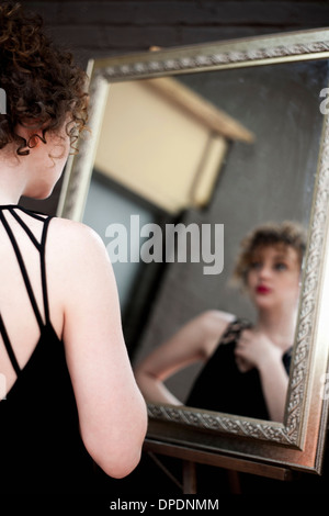 Young woman looking at reflection in mirror