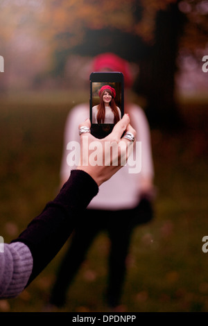 Hand holding smartphone, taking photograph of young woman Stock Photo
