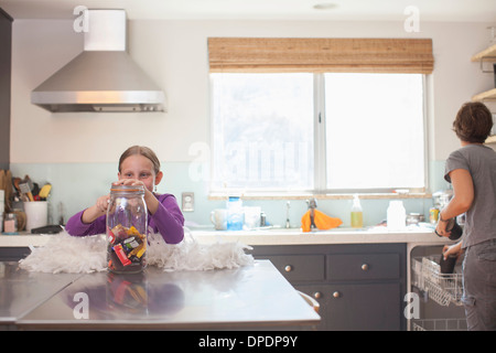 Daughter secretly getting biscuit from biscuit barrel Stock Photo
