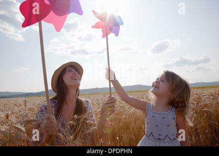 Mother and daughter in wheat field holding windmill Stock Photo