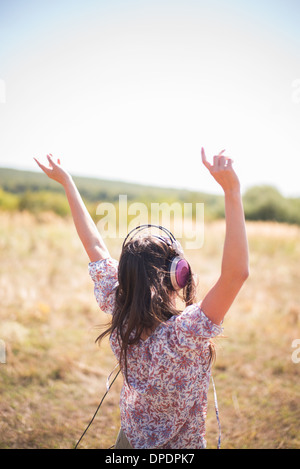 Portrait of mid adult woman dancing in field with arms raised, wearing headphones Stock Photo