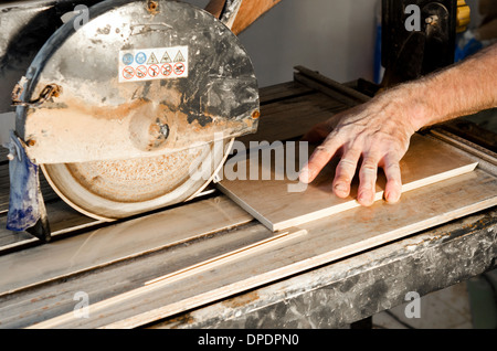 A wet saw cutter is being used to cut floor tile Stock Photo
