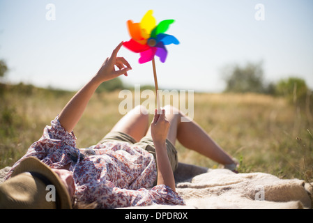 Woman lying in on back holding windmill Stock Photo