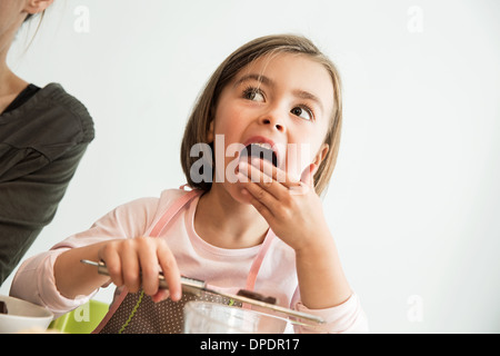 Girl licking batter from fingers Stock Photo