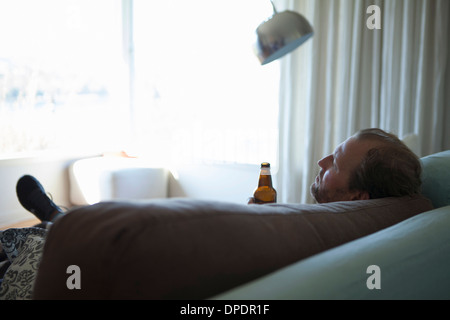 Mature man with eyes closed reclining on sofa Stock Photo