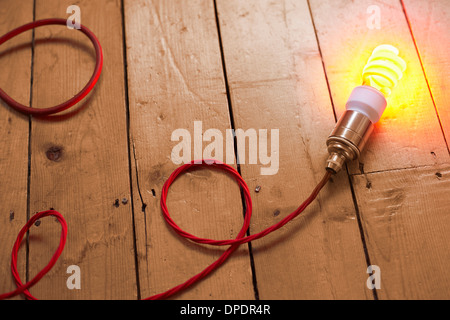 Still life of energy saving lightbulb on wooden floorboards Stock Photo