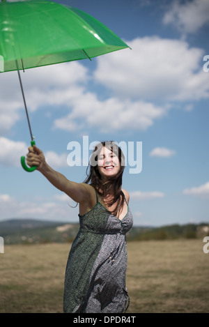 Mid adult woman holding green umbrella Stock Photo