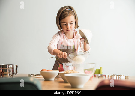 Girl sieving flour into mixing bowl Stock Photo