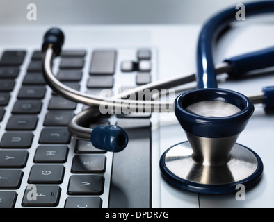 Stethoscope sitting on laptop illustrating online healthcare and doctor's desk Stock Photo