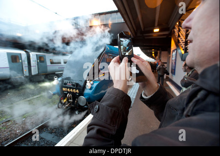 Man using cameraphone to take a picture of a steam engine at York station. Stock Photo