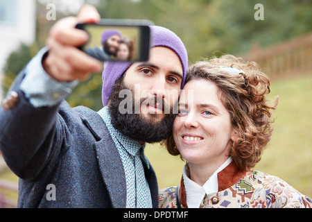 Couple taking a photograph of themselves with a smartphone outdoors Stock Photo